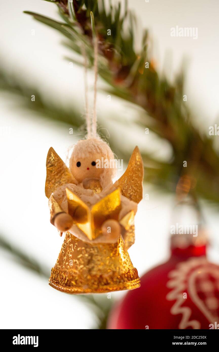 Geschmückter Weihnachtsbaum, echte Nordmann-Tanne vor verschwommenem Hintergrund. Makrofotografie zeigt einen goldenen Engel aus Holz und Papier. Stockfoto