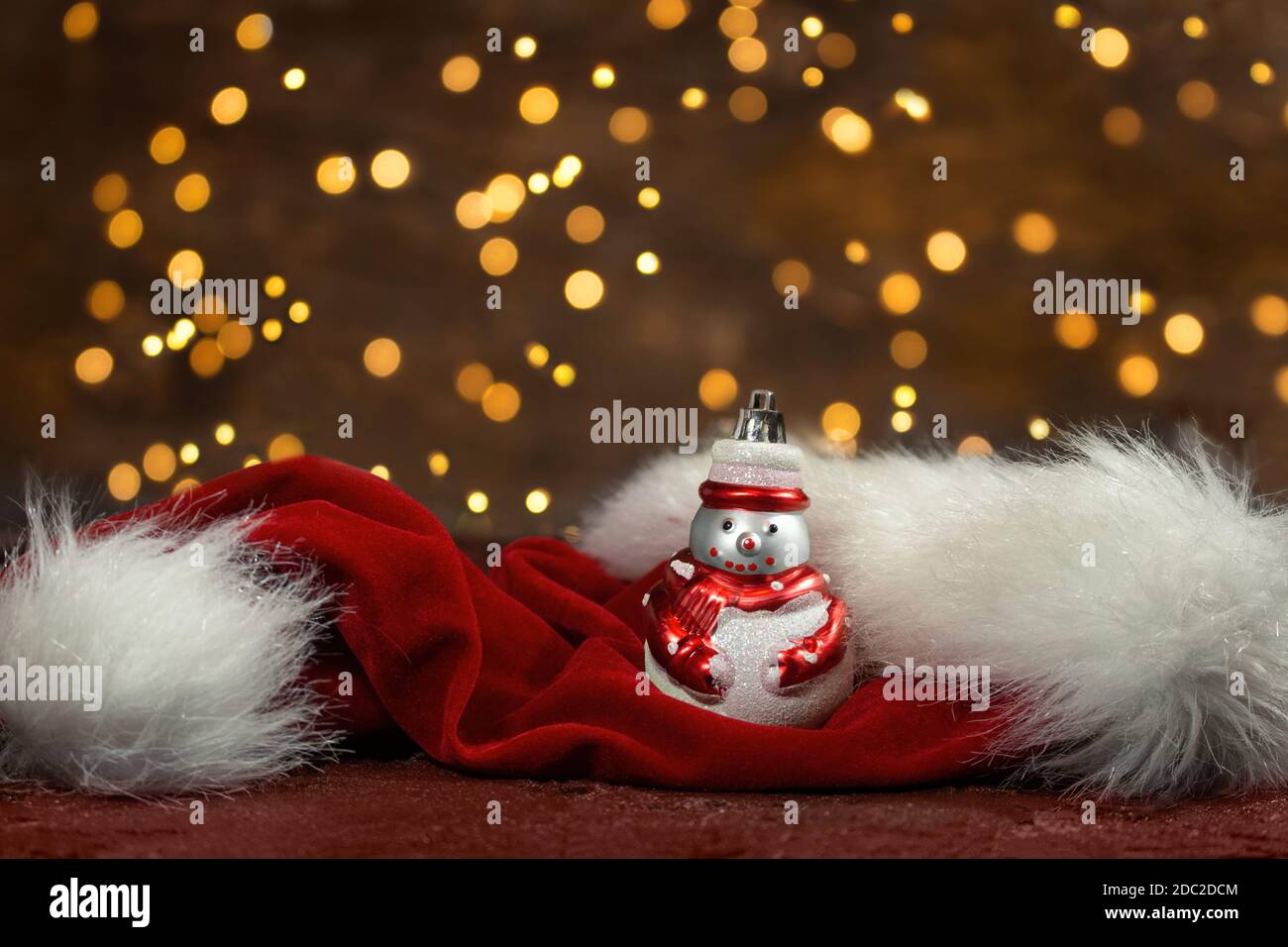 Schneemann und roter weihnachtsmann Hut mit Neujahr Lichter im Rücken. Unscharfer Hintergrund. Weihnachtskarte Stockfoto