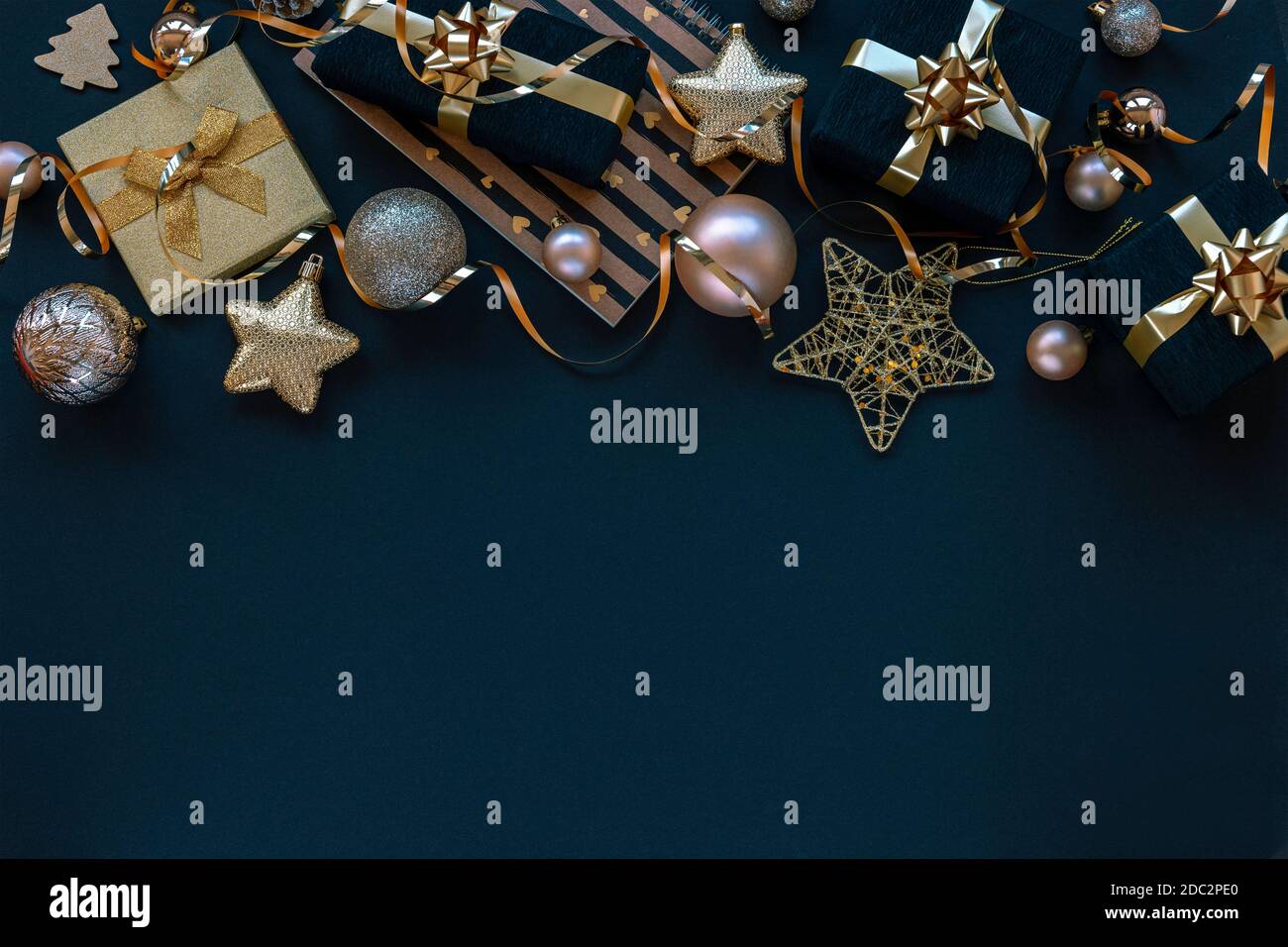 Neujahrsgeschenke in schwarzen Schachteln, Weihnachtsspielzeug und Girlande auf schwarzem Hintergrund. Draufsicht, flach liegend, Kopierbereich. Stockfoto