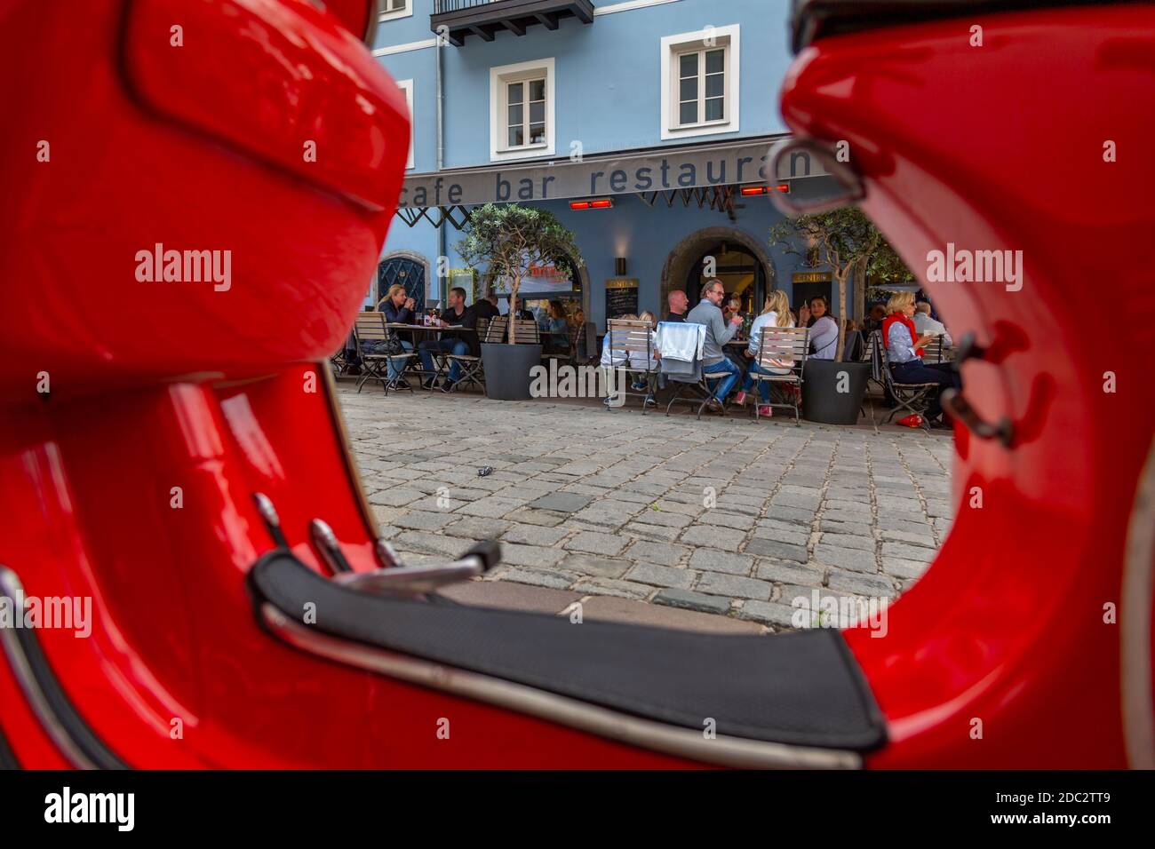 Blick auf die Besucher, die Drinks vor dem Café genießen, umrahmt von einem roten Roller auf Vorderstadt, Kitzbühel, Österreich, Europa Stockfoto