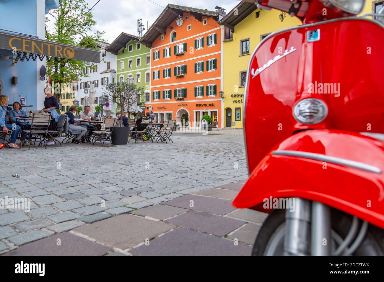 Blick auf die Besucher, die Drinks vor dem Café genießen, umrahmt von einem roten Roller auf Vorderstadt, Kitzbühel, Österreich, Europa Stockfoto