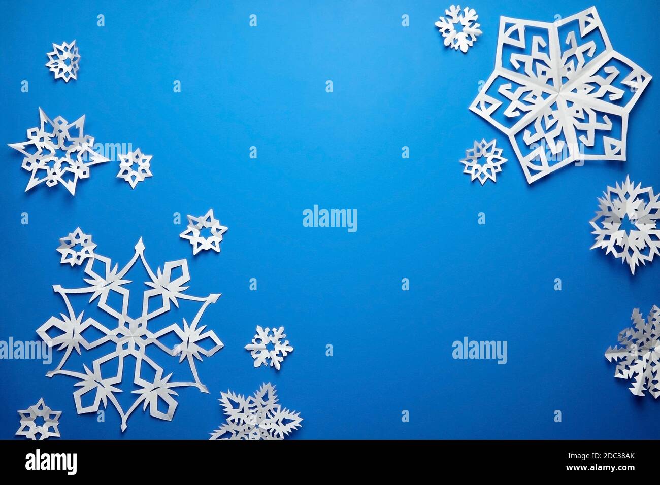 Komposition mit weißen Papier Schneeflocken auf blauem Hintergrund Stockfoto