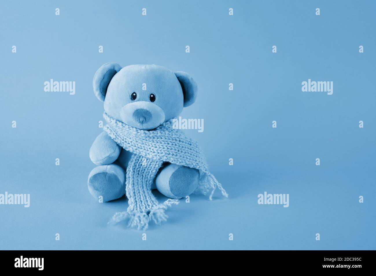 Blauer Teddybär mit Schal auf blauem Hintergrund. Blue monday Konzept. Stockfoto