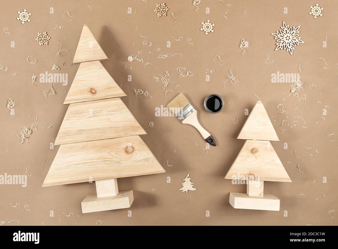 Komposition ZU WEIHNACHTEN oder Neujahr. Handgemachte Weihnachtsbäume aus Holz, Farbe, Pinsel auf hellbeigem Hintergrund. Konzept Zero Waste, Eco - Friendly Merry Chri Stockfoto