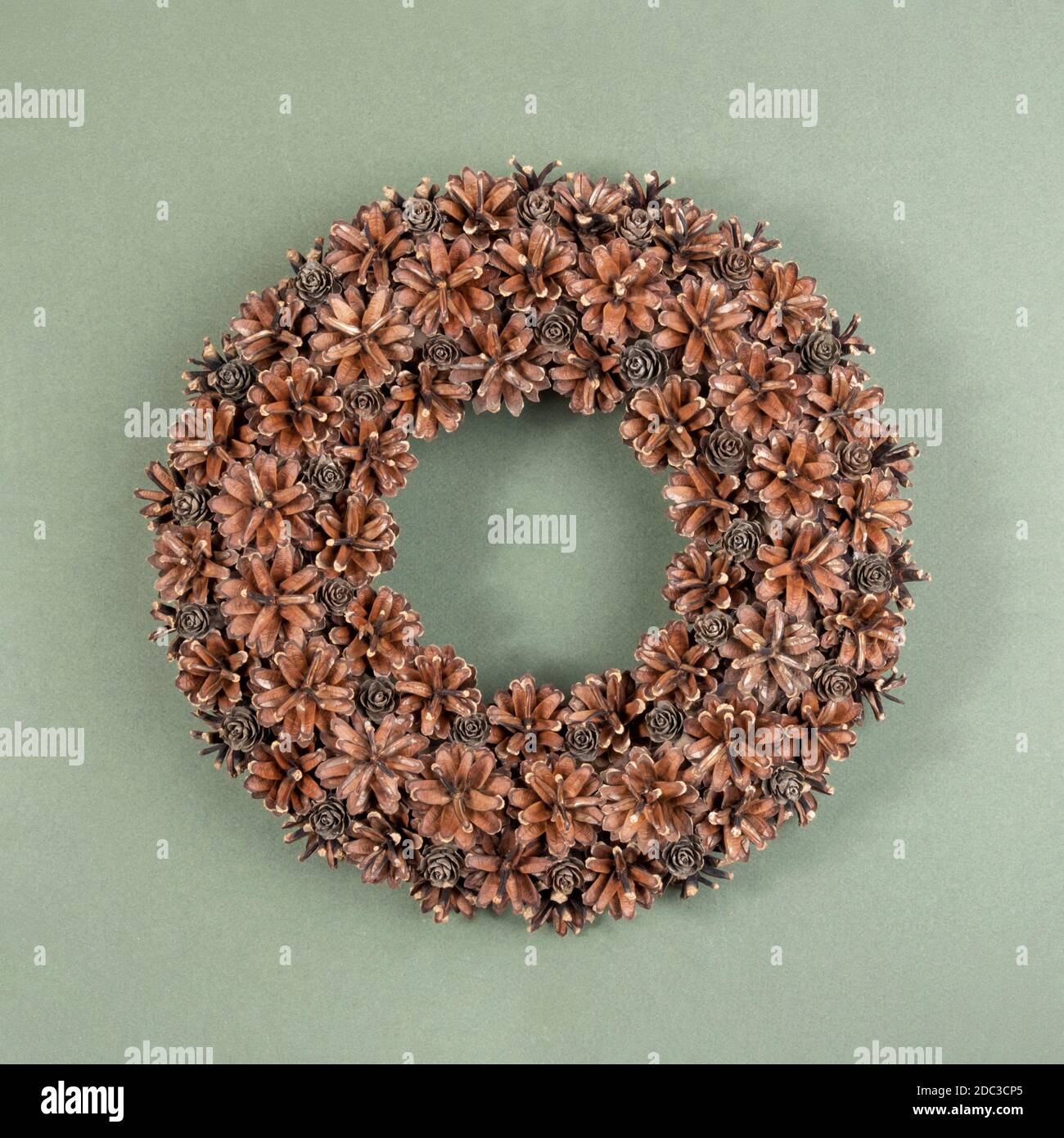 Traditioneller weihnachtlicher festlicher Kranz aus natürlichen Tannenzapfen auf grünem Hintergrund. Konzept handgemachte umweltfreundliche Einrichtung aus natürlichen Materialien, Weihnachten Stockfoto