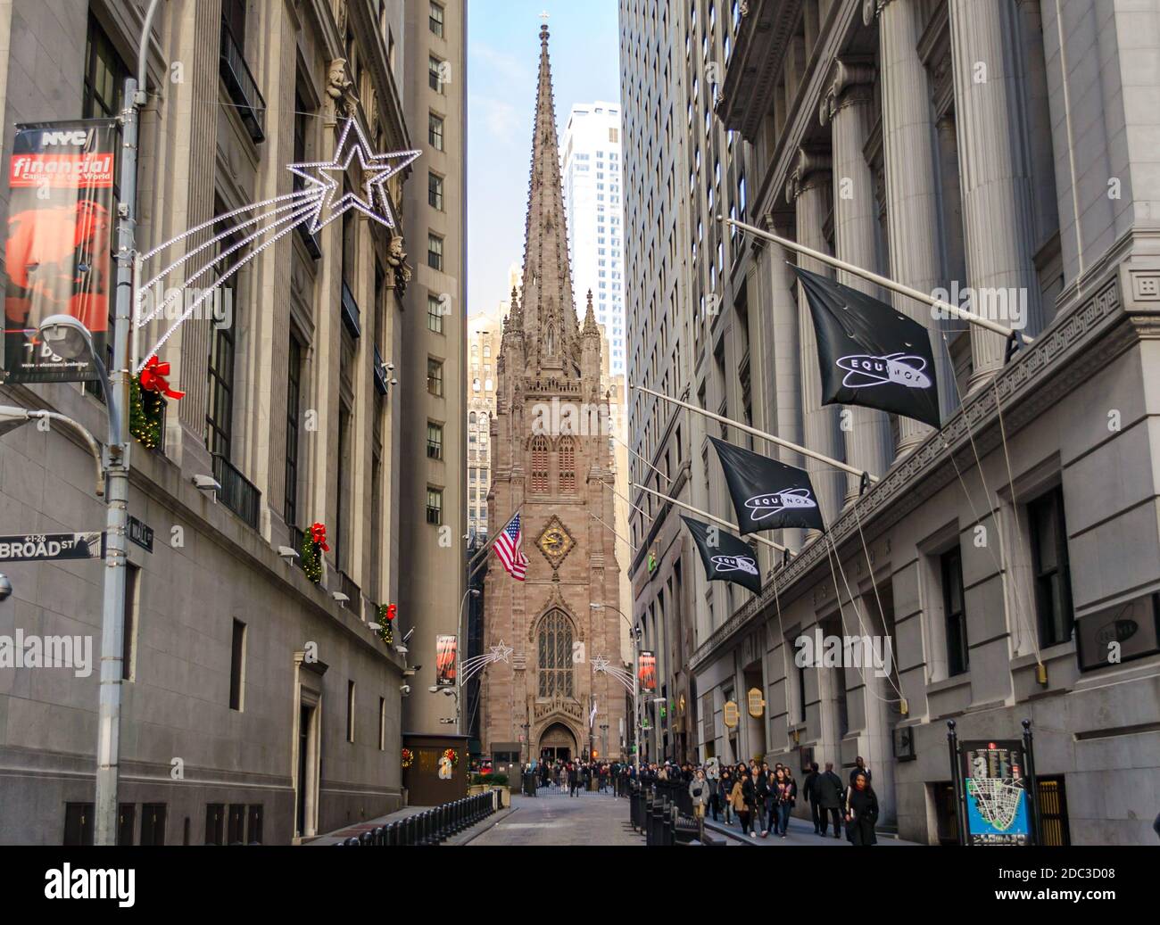 Trinity Church an der Kreuzung von Wall Street und Broadway in Lower Manhattan, New York, USA. Straße gekleidet in Weihnachten Feiertagsstimmung Stockfoto