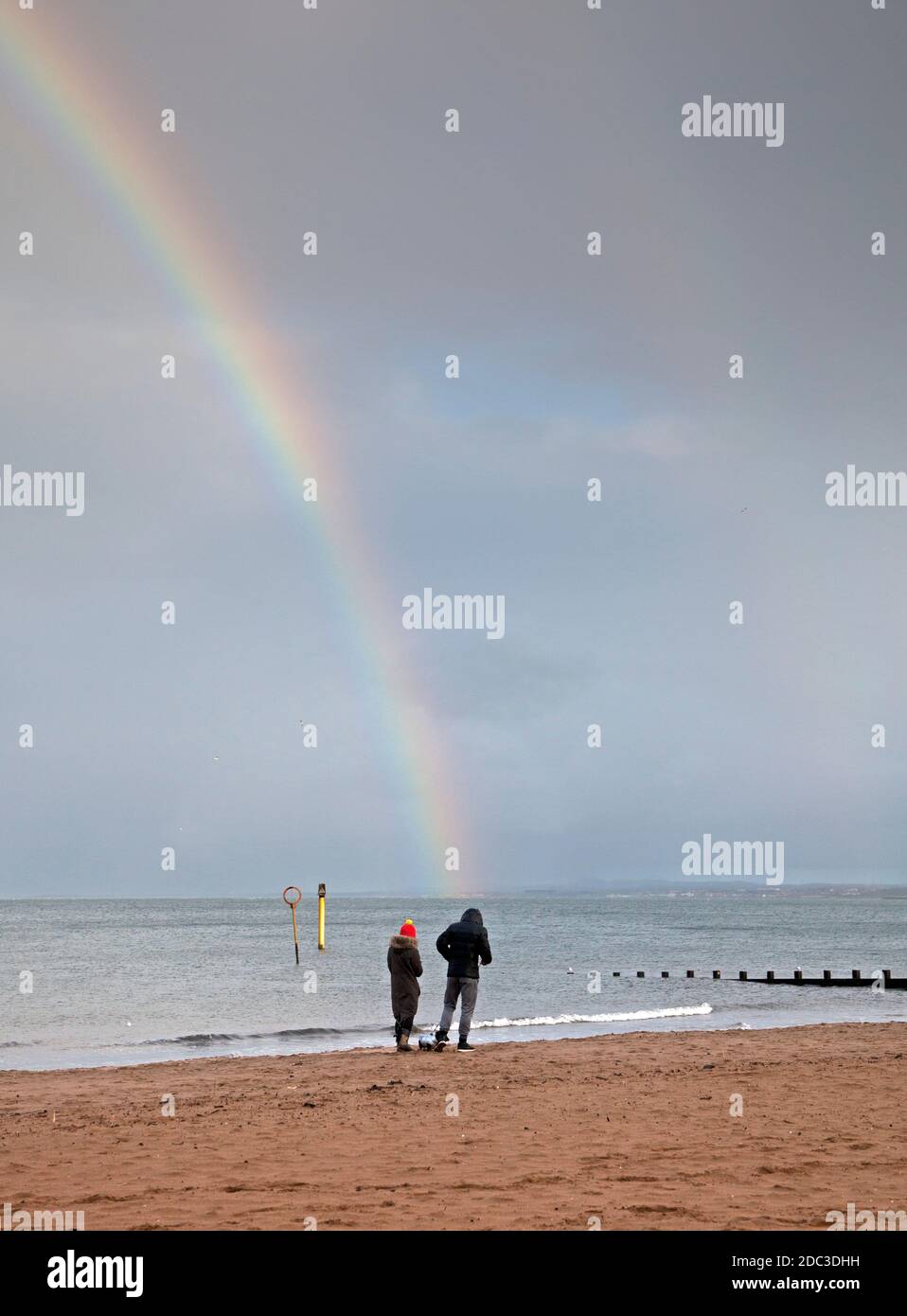 Portobello, Edinburgh, Schottland, Großbritannien. 18. November 2020. Regenbogen am Meer, 10 Grad, aber windchill macht es kühler für dieses Paar, das an der Küste des Firth of Forth läuft. Quelle: Arch White/Alamy Live News. Stockfoto