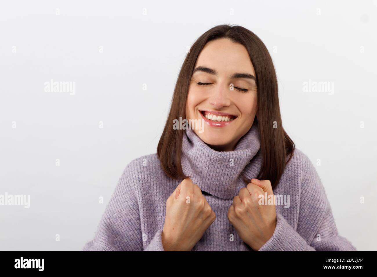 Nahaufnahme verführerisch glücklich lächelnde Brünette Frau in einem lila Pullover freuen sich auf spannende Veranstaltung, grinsend freudig Ausdruck Positivität Stockfoto
