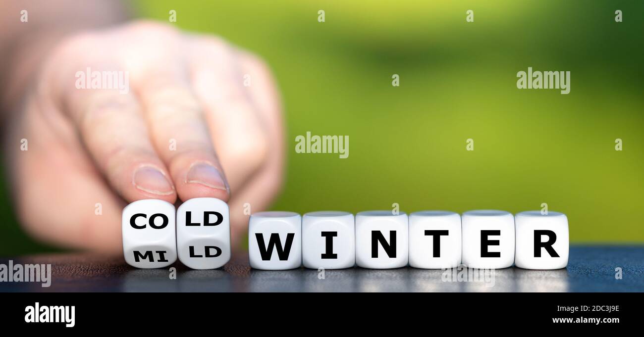 Hand dreht Würfel und ändert den Ausdruck 'milder Winter' in 'kalten Winter'. Stockfoto