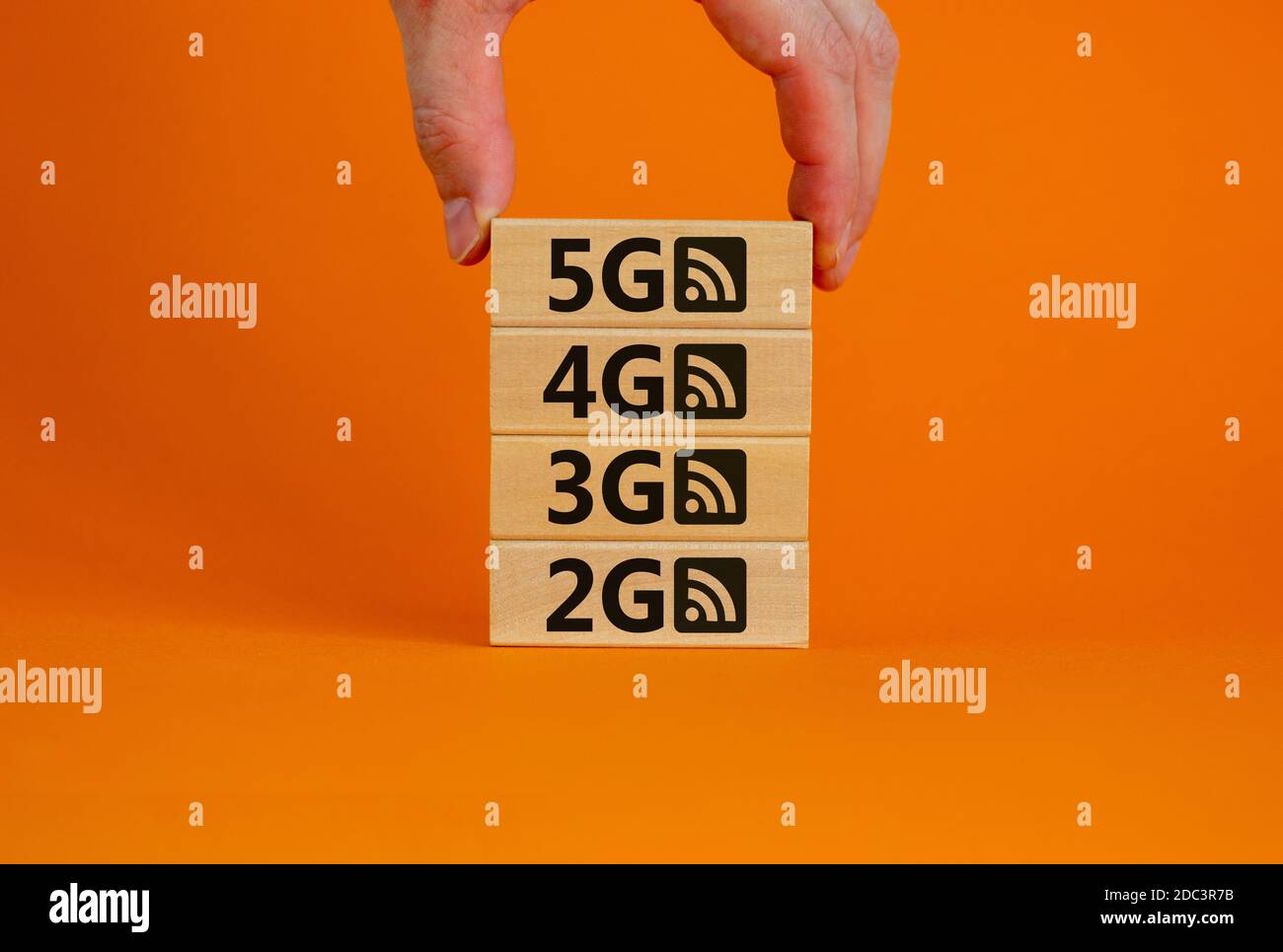 5G Network Evolution Konzept. Hand hält einen Holzblock mit Text und Symbol. Speicherplatz kopieren. Schöner orangefarbener Hintergrund. Stockfoto