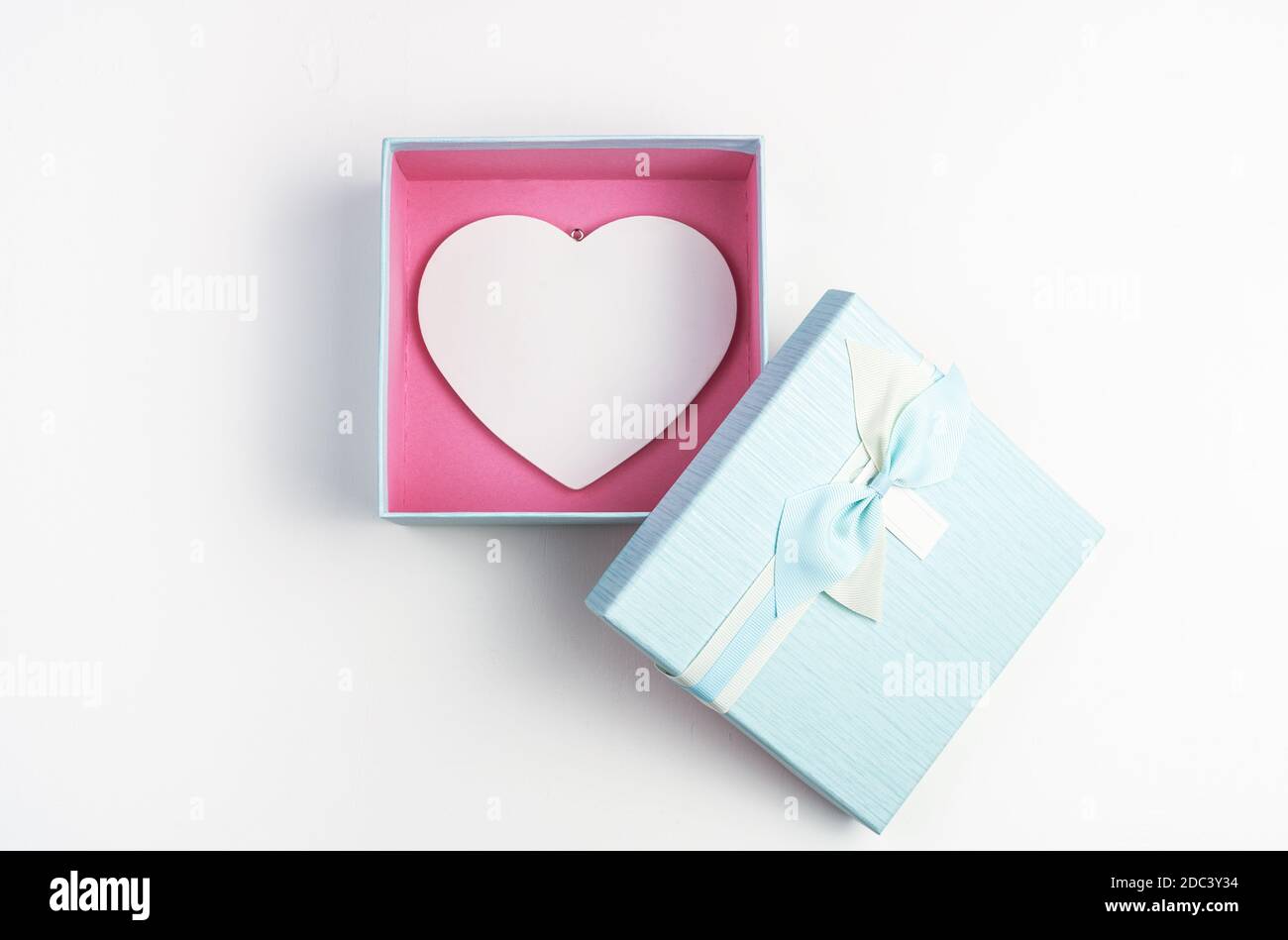 Weißes Herz in einer blauen Box mit offenem Deckel auf weißem Hintergrund. Stockfoto