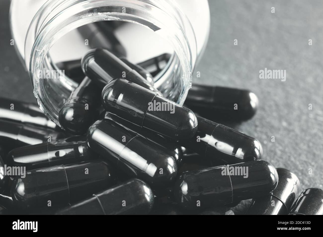 Nahaufnahme Bild von schwarzen Kapseln verschütten aus dem Behälter, selektive Fokus, Farbtonung angewendet. Stockfoto