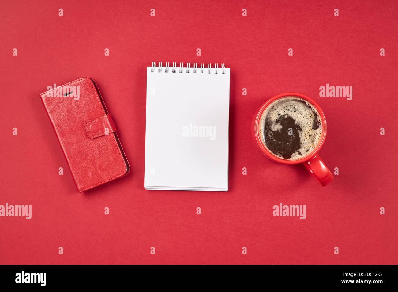 Roter Büroschreibtisch mit Note, Smartphone und Tasse Kaffee. Stockfoto