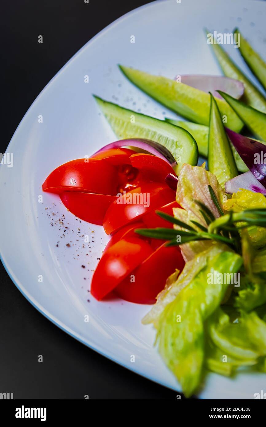 Frisches Gemüse serviert auf weißem Teller für Snack im Restaurant.Rot Tomaten, grüne Gurken & Salat für Keto Ernährung Stockfoto