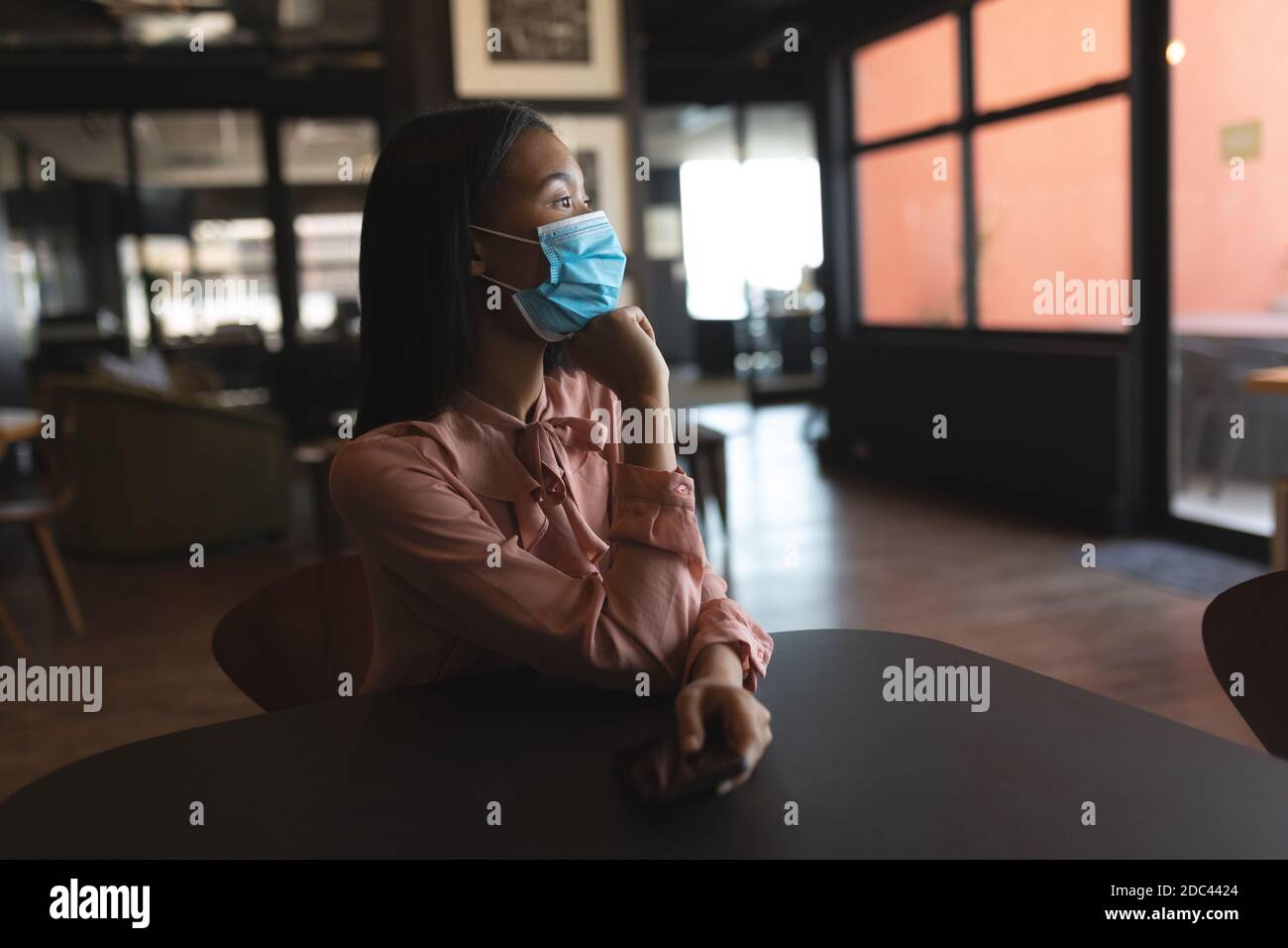 Asiatische Frau trägt Gesichtsmaske sitzen im modernen Büro Stockfoto