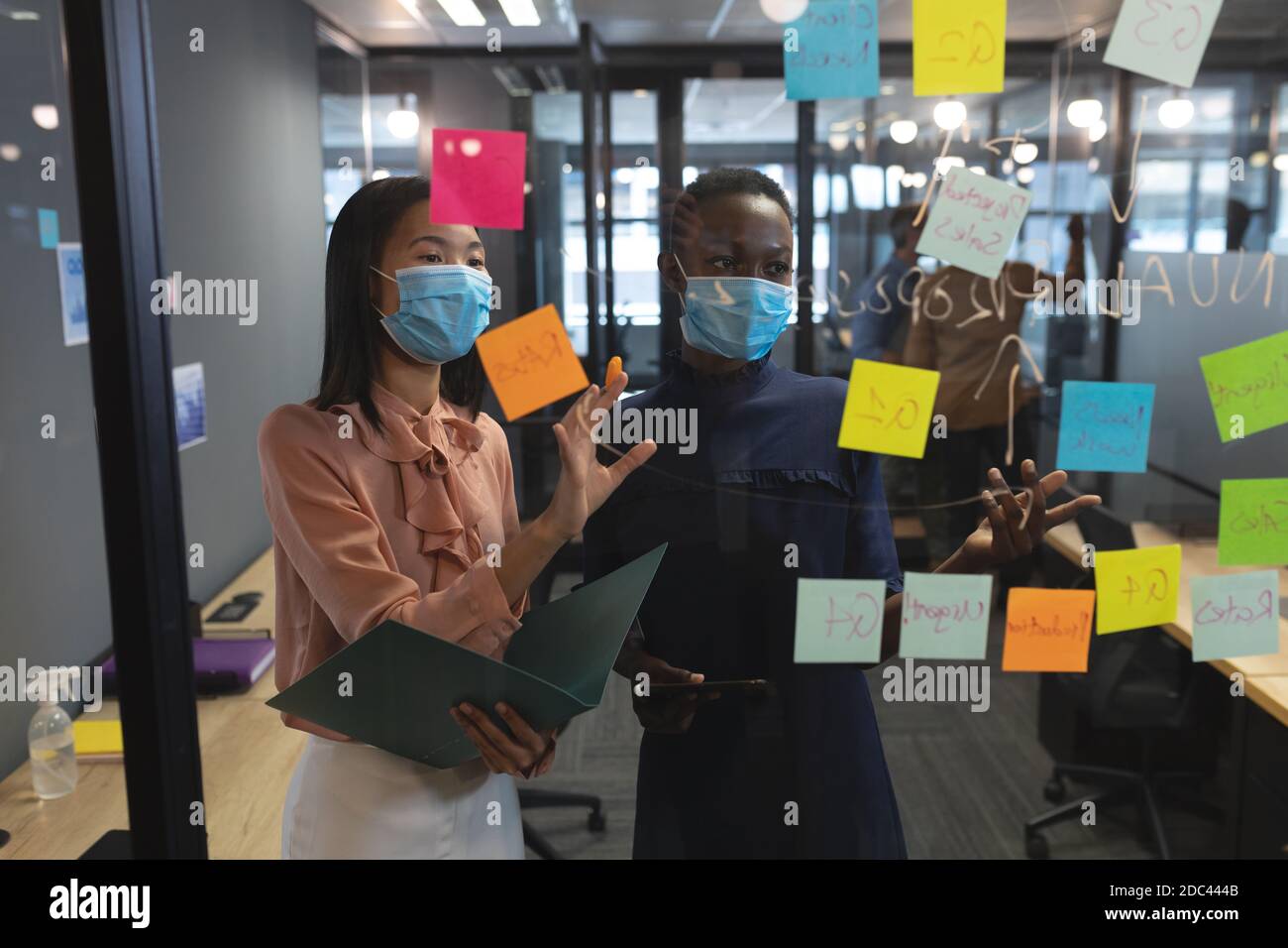 Verschiedene weibliche Kollegen tragen Gesichtsmasken Brainstomeln im Büro Stockfoto