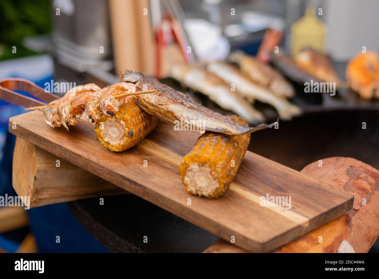 Gegrillte Garnelen, Garnelenspieße und Maiskolben auf Holzschneidebrett Stockfoto