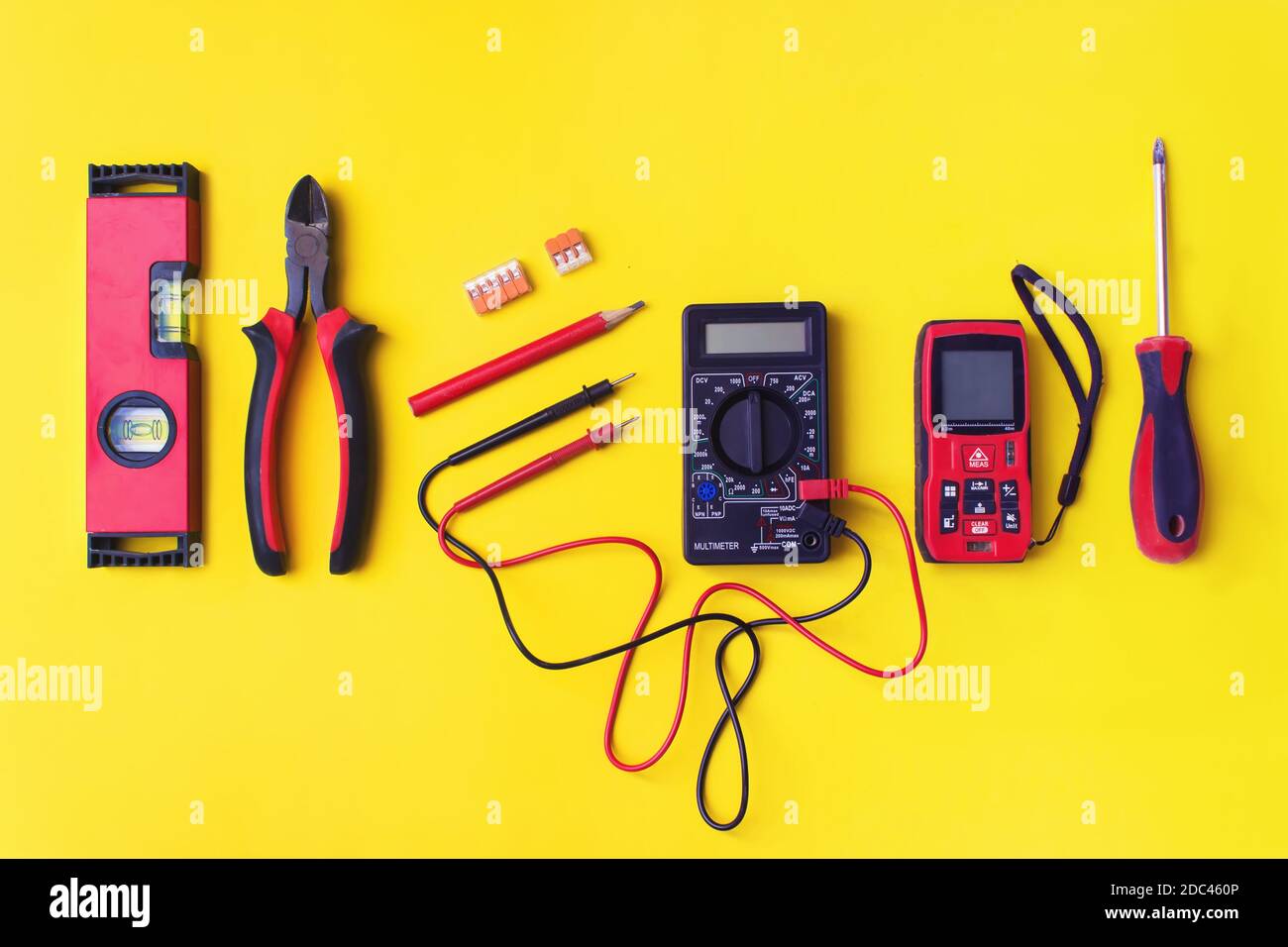 Verschiedene Elektriker-Zubehör auf gelbem Hintergrund. Hintergrund der professionellen Elektriker Werkzeuge mit Platz für Text Stockfoto
