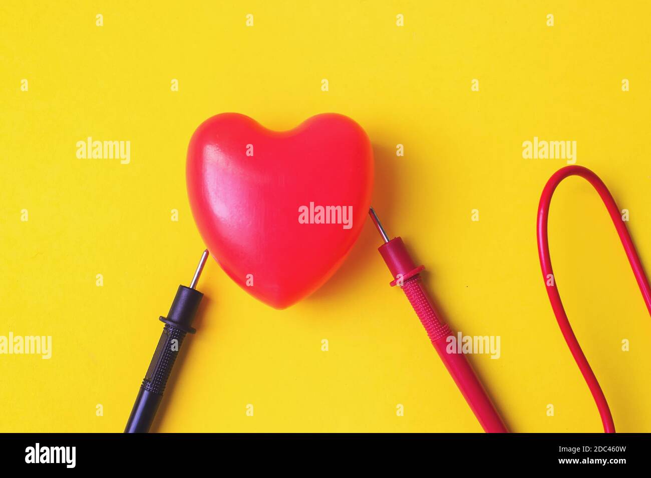 Vitalenergie-Konzept. Rotes Herz mit Multimetersonden auf gelbem Hintergrund. Liebe, Technologie-Konzept. Alles Liebe zum Valentinstag. Liebe, Hochzeit. Top Vie Stockfoto