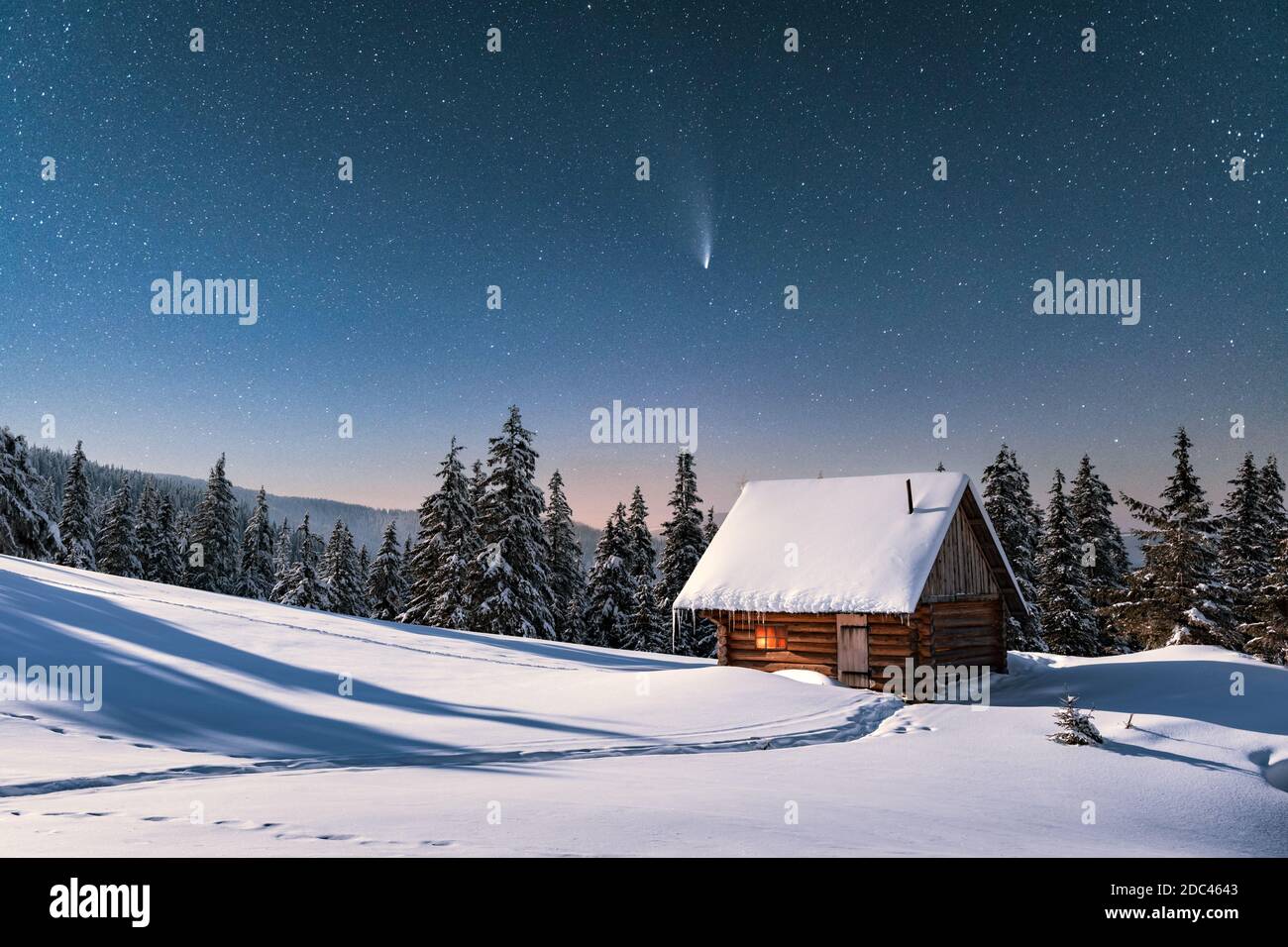 Fantastische Winterlandschaft mit Holzhaus in verschneiten Bergen. Sternenhimmel mit Kometen und schneebedeckter Hütte. Weihnachtsurlaub und Winterurlaub Konzept Stockfoto