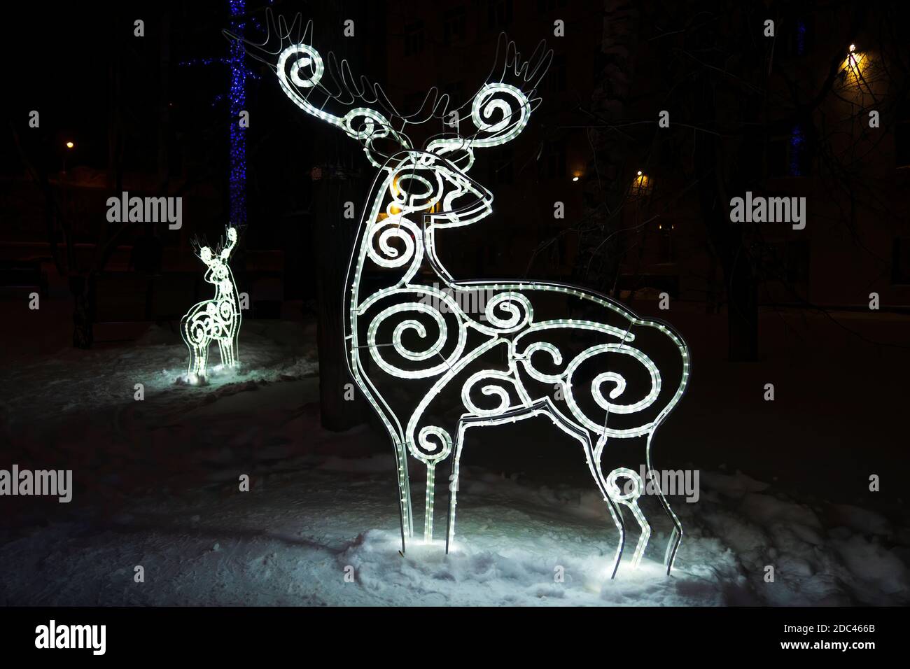 Hirschfigur aus glühender Girlande in dunkler Winternacht im Schnee. Weihnachtliche Straßendekorationen Stockfoto