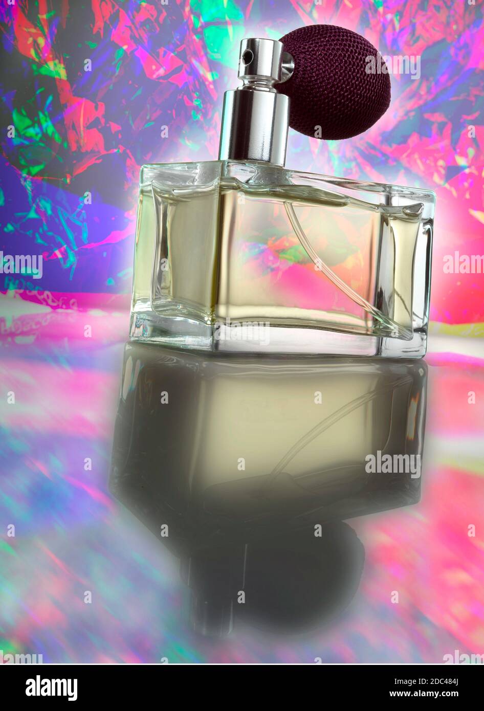 Glas Parfüm Flasche mit Zerstäuber Glühbirne Spray. Fotografiert in einem niedrigen Winkel mit dramatischer Beleuchtung und einem psychedelischen, farbenfrohen Hintergrund. Stockfoto