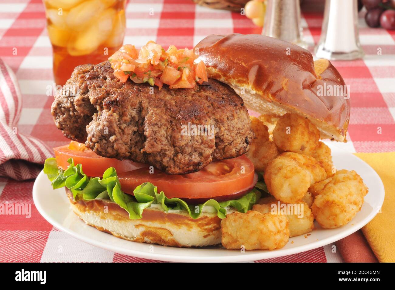 Ein hahner Hamburger auf einem Brezelbrötchen mit Tater Tots Stockfoto