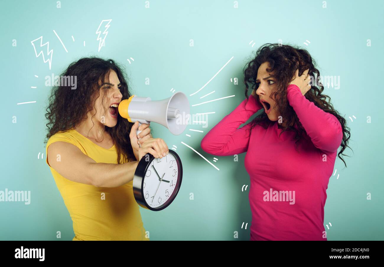 Frau schreit mit Lautsprecher zu einem Freund, weil es zu spät ist. Wütend Ausdruck. Cyan Hintergrund Stockfoto