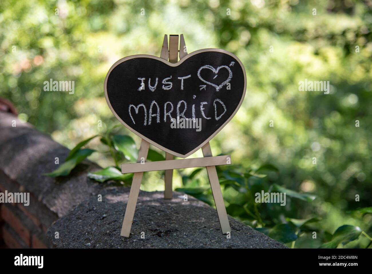 Gerade verheiratet Zeichen in der Form eines hölzernen Herzen, Foto im Park aufgenommen, die eine schöne grüne Farbe hinter bietet Stockfoto