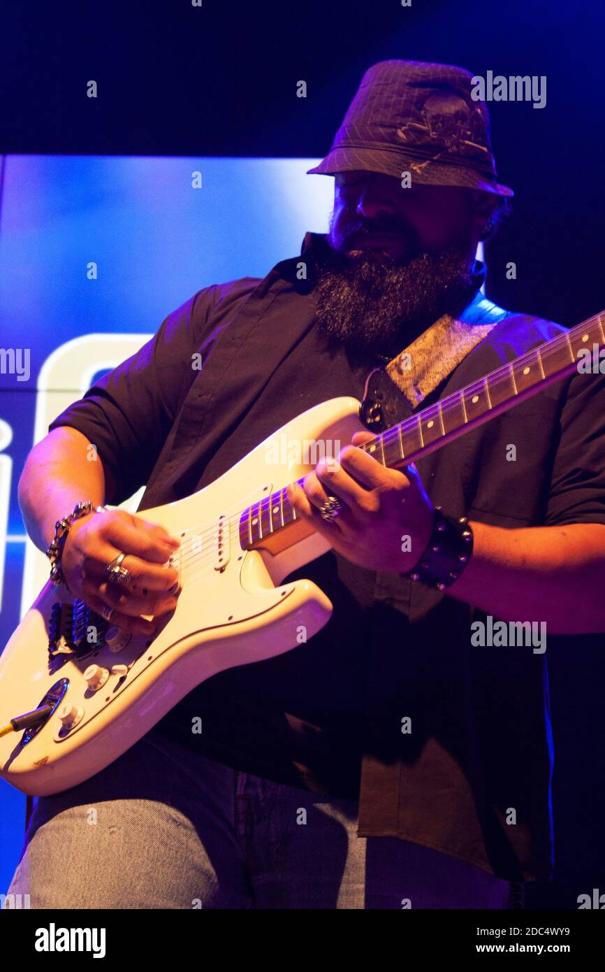 Bärtiger Mann im Hut, der Gitarre spielt und unter Blau Saiten spielt Licht in Mexiko Stadt Stockfoto