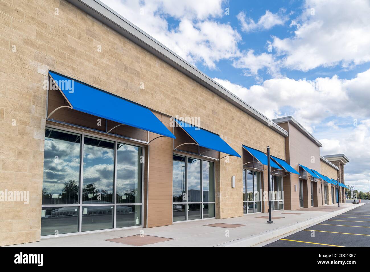 Brandneu, ohne Logo, Beschilderung oder Label-Schaufenster einer im Bau befindlichen Mall in den USA mit blauen Markisen über dem Eingang, blau bewölktem Himmel Ref Stockfoto