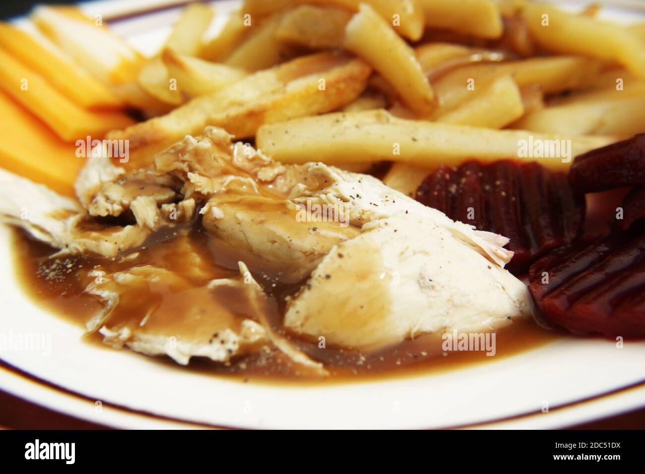 Eine zubereitete Mahlzeit mit Huhn in Soße, pommes frites, Käse und Rüben Stockfoto