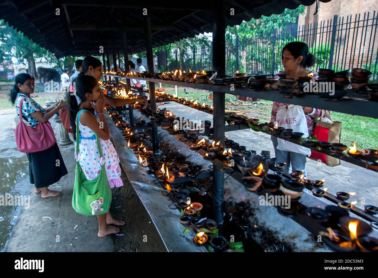 Während des Esala Perahera Festivals leuchten im Tempel der Heiligen Zahnreliquie in Kandy in Sri Lanka die Gläubigen mit leichten Öllampen. Stockfoto