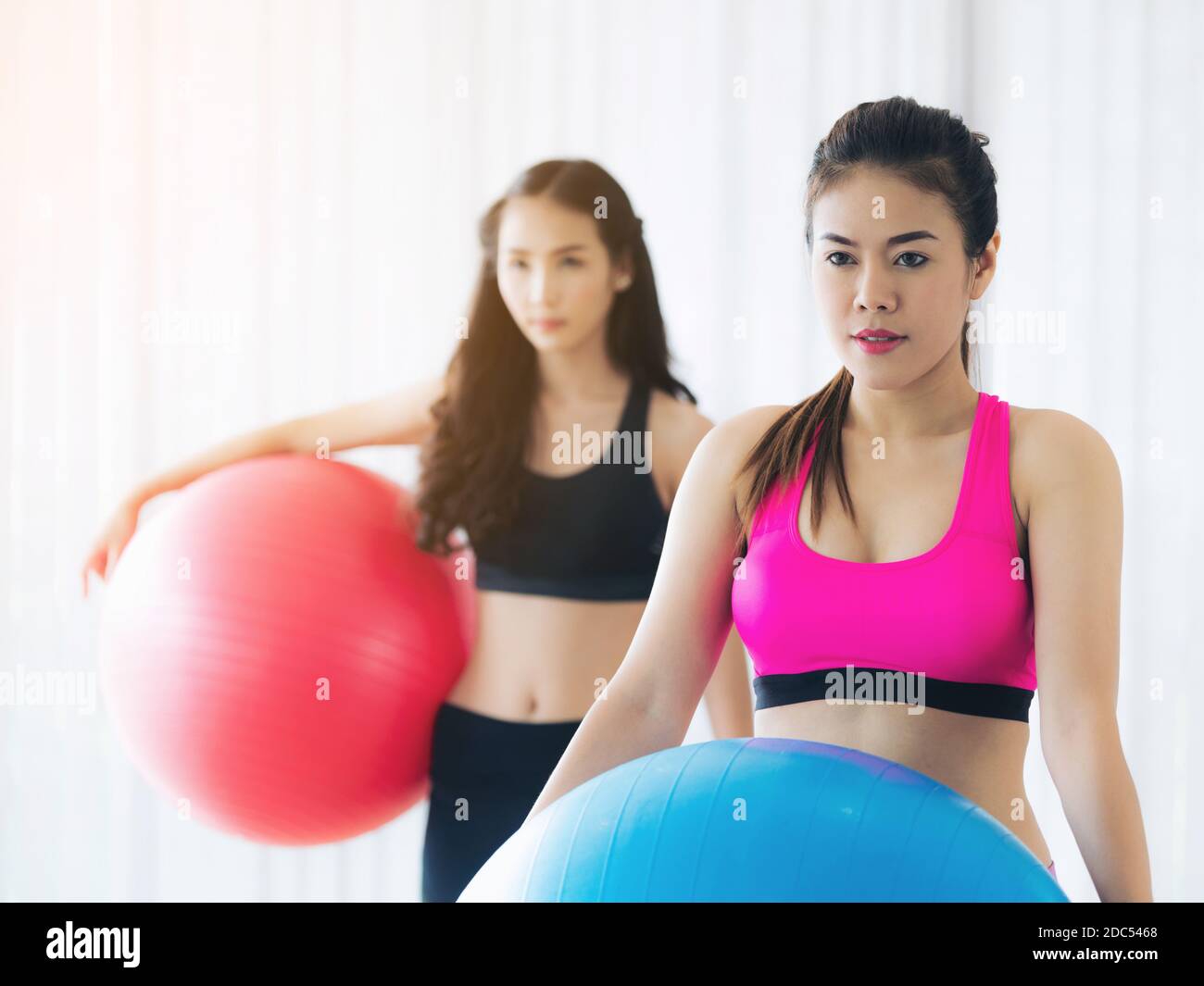 Zwei gesunde Frauen halten Fit Ball in der Fitness-Gym-Gruppenübung. Sport Lifestyle-Konzept. Stockfoto