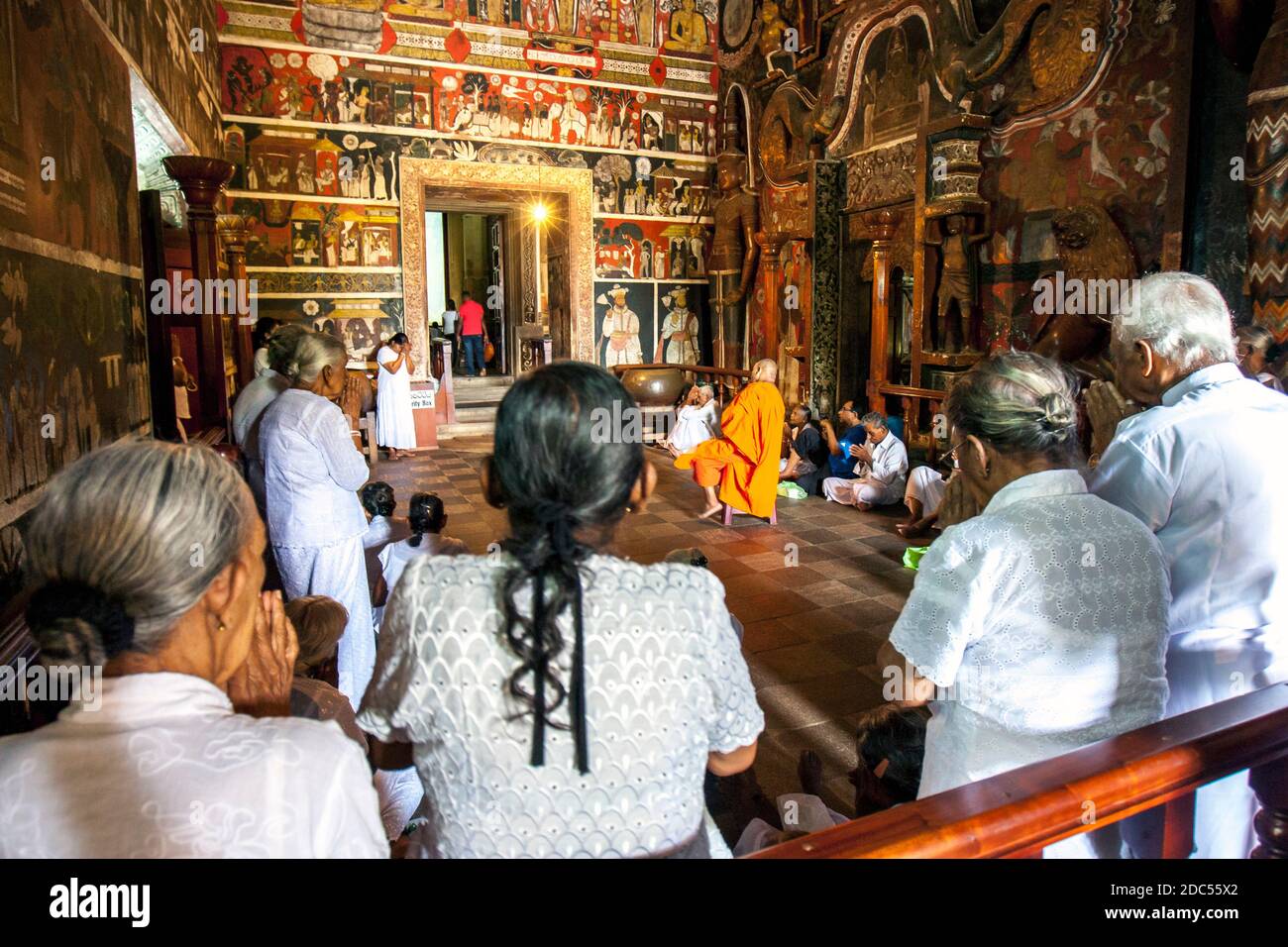 Ein buddhistischer Mönch hält Hof im Schreinraum bei Kelaniya Raja Maha Vihara in der Nähe von Colombo in Sri Lanka, während Pilger beten. Stockfoto