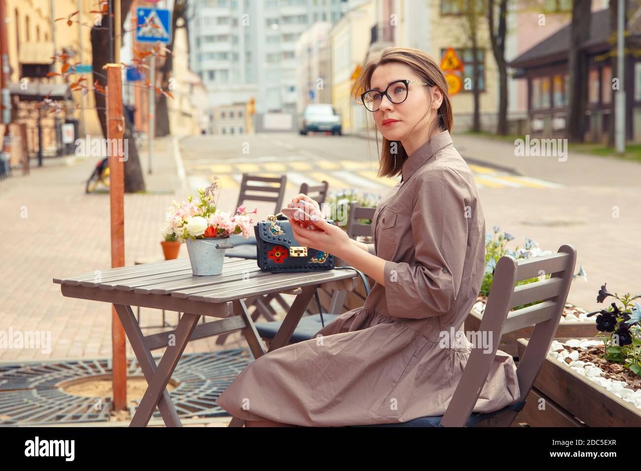 Schöne Frau Reisende auf der Straße der Altstadt. Geschäftsfrau sitzt an einem Tisch in einem Sommercafé und spricht am Telefon Stockfoto