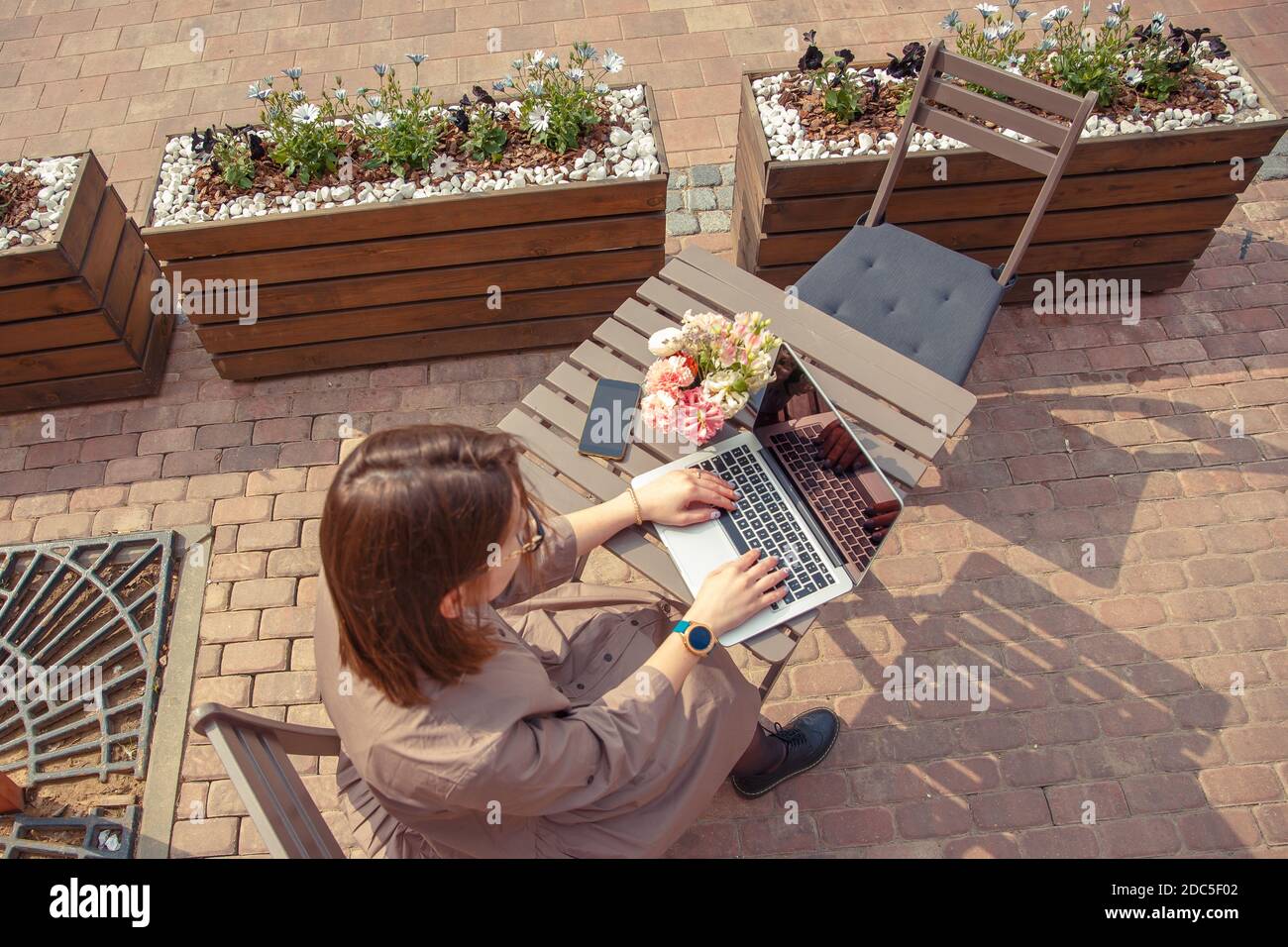 Schöne Frau Reisende auf der Straße der Altstadt. Geschäftsfrau sitzt an einem Tisch in einem Sommercafé und arbeitet an einem Computer Stockfoto