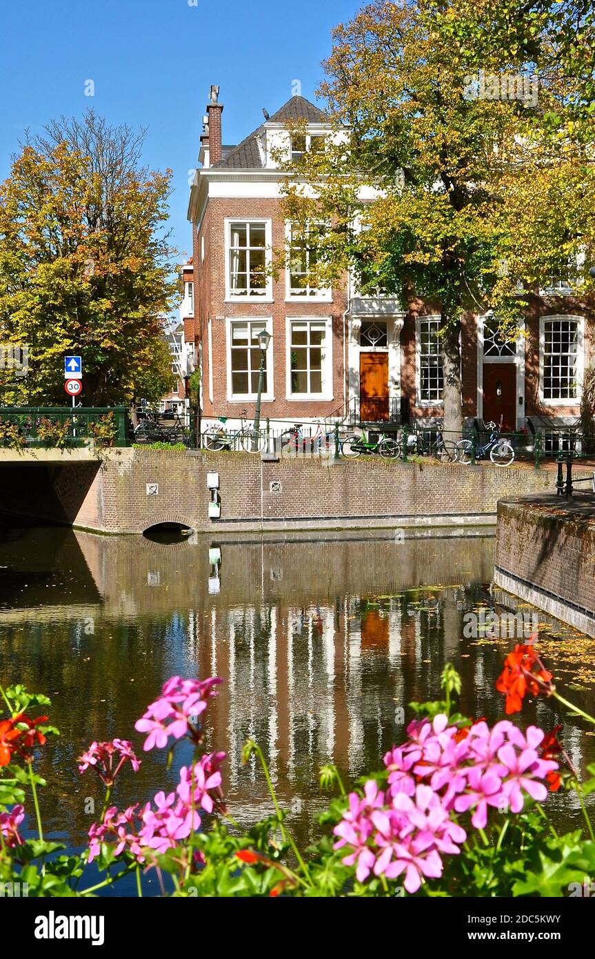 Typisch holländische Kanalszene mit traditionellem holländischem Gieblehaus, Fahrrädern und bunten Blumen. Stockfoto