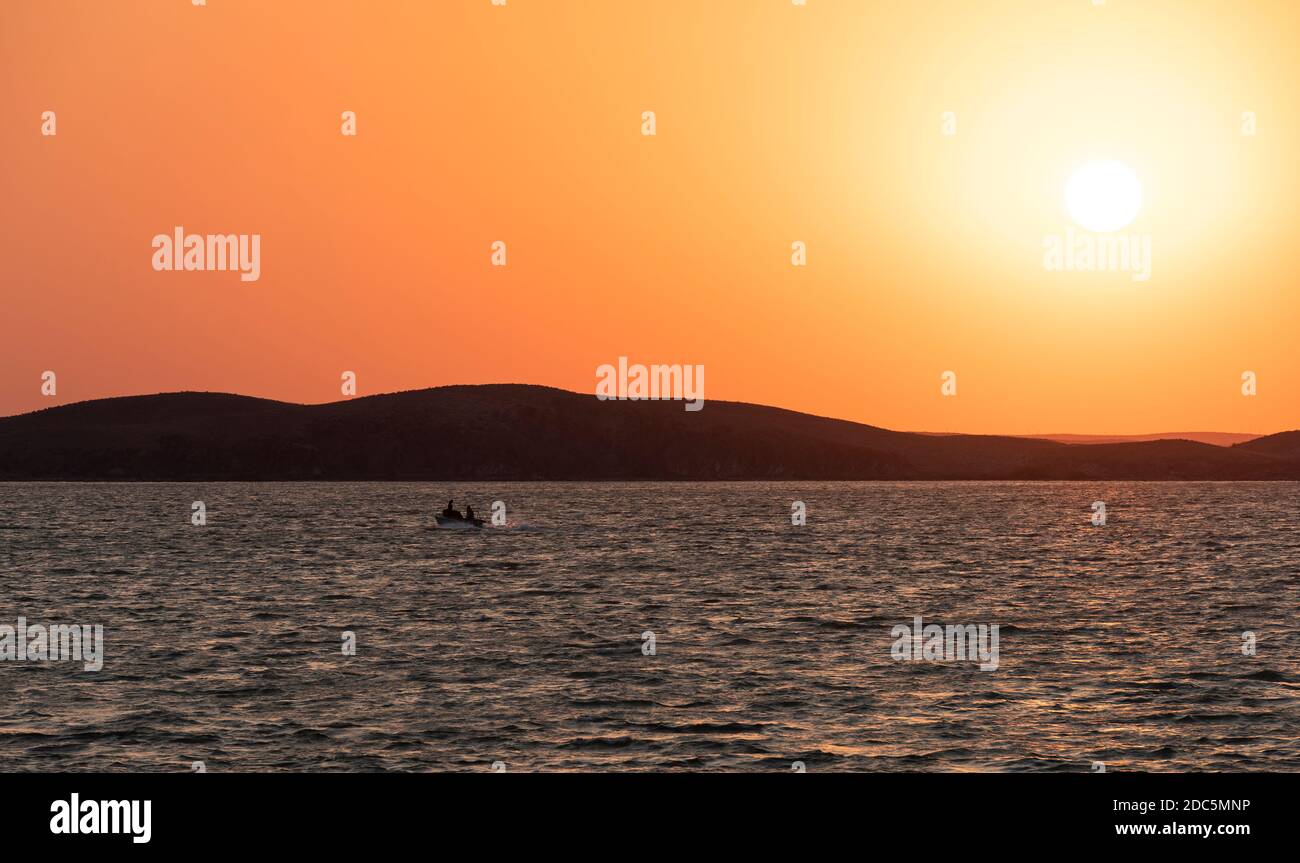 Alakol, Kasachstan - 22. Juli 2019: Motorboot auf Alakol See bei Sonnenuntergang mit orangefarbenem Himmel an einem Sommertag. Stockfoto