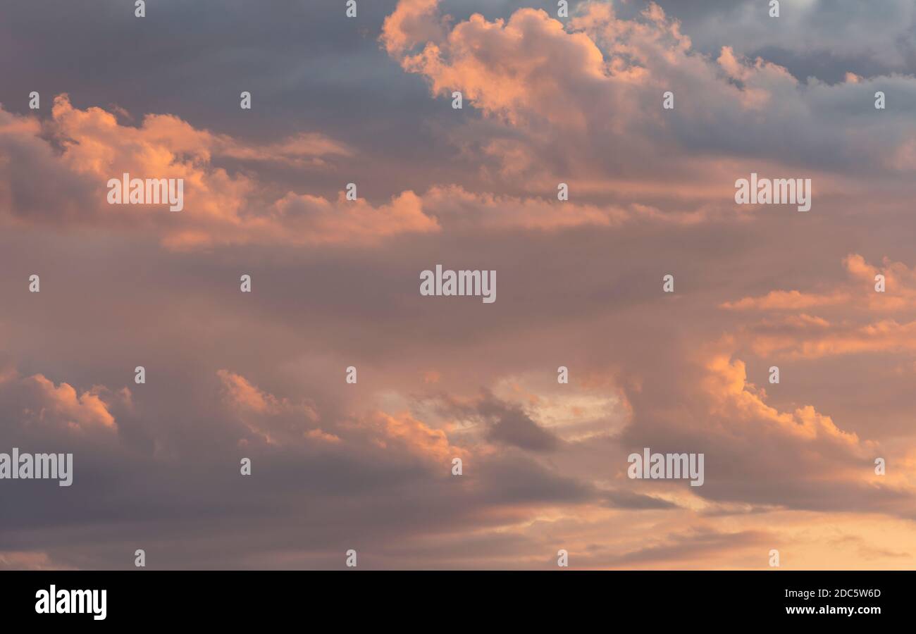 Orangefarbener Himmel bei Sonnenuntergang mit dunkelschwarzen und grauen Regenwolken. Stockfoto