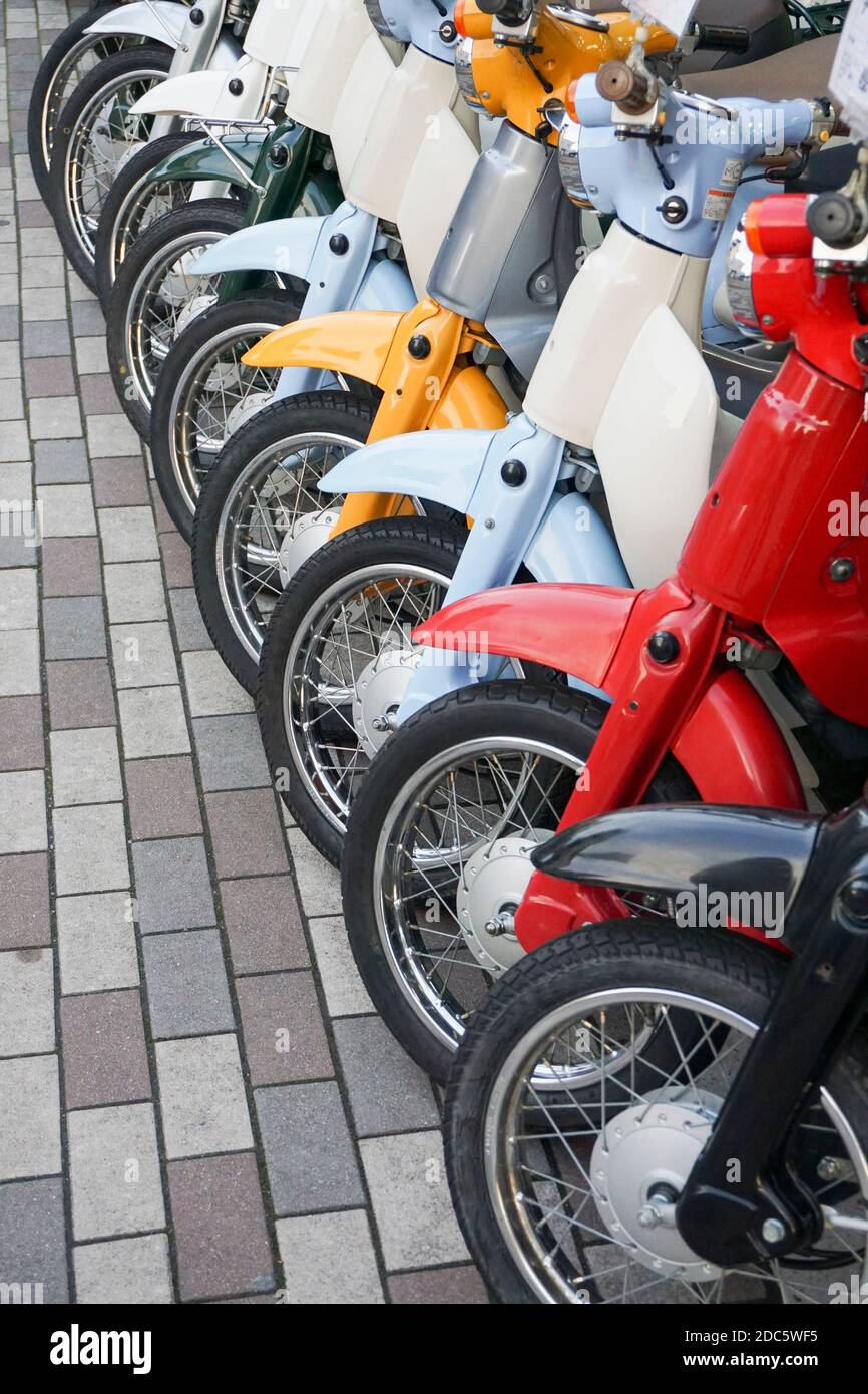 Mehrfarbige Vermietung Motorroller in einer Reihe auf Bürgersteig, Kyoto, Japan geparkt Stockfoto