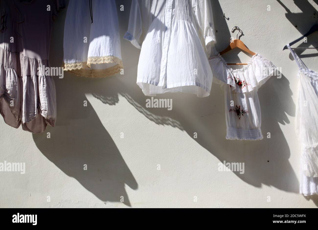 Eine Nahaufnahme von hängenden Kleidern während eines hellen Sonnenaufgangs, die auf die Kleidung in Ibiza, Spanien gerichtet ist Stockfoto