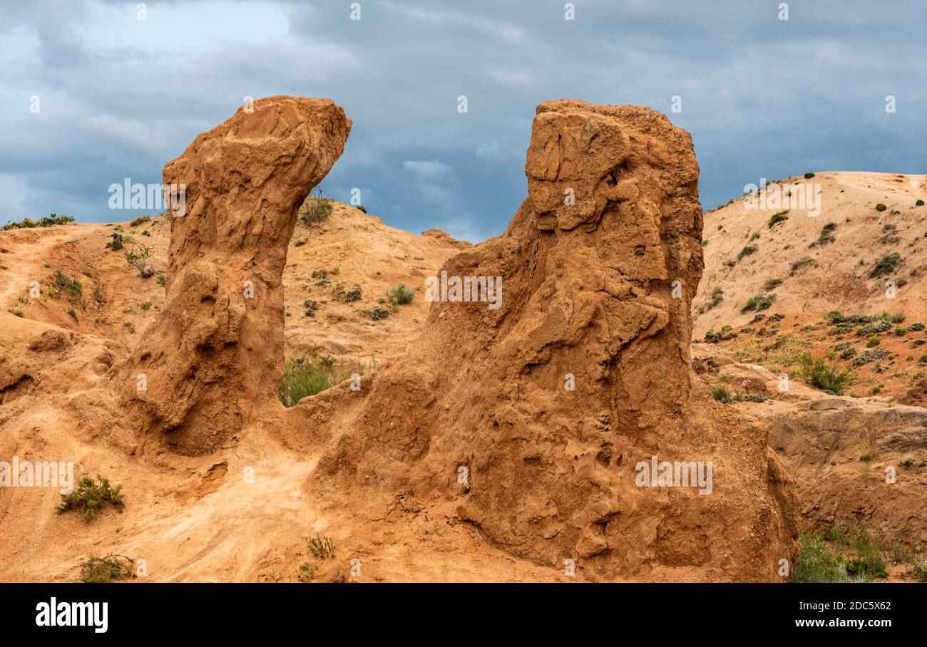 Märchenhafte Schlucht am Issyk-kul-See in Kirgisistan mit roten Bergen und dunklem Regenhimmel. Stockfoto