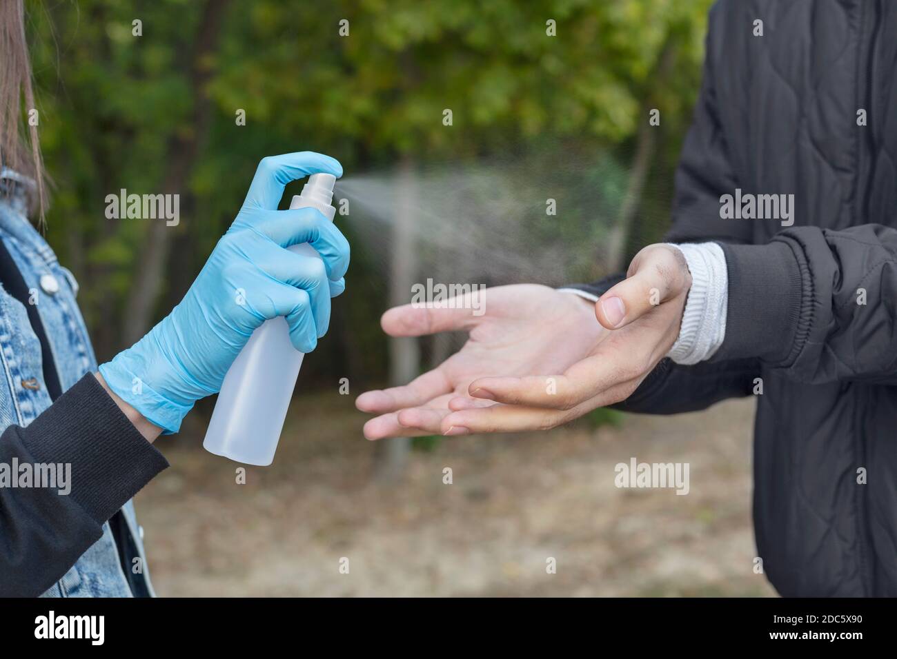 Nahaufnahme Frau in Schutzhandschuhen sprühen Freund mit der Hand Desinfektionsmittel Stockfoto