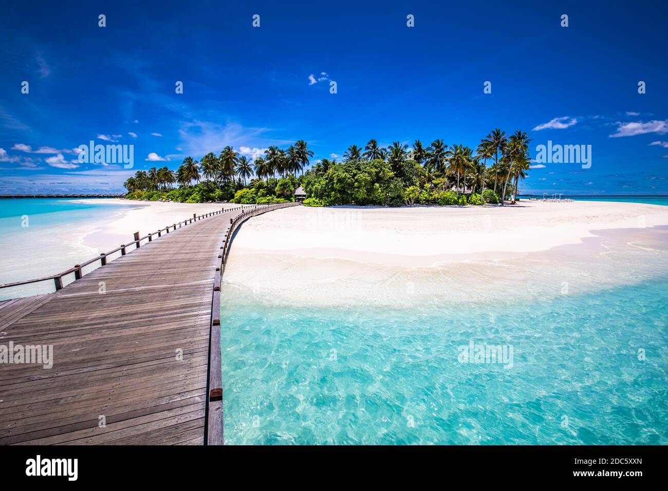 Malediven Strandresort Panoramalandschaft. Tropischer Urlaub am Strand. Langer hölzerner Pier, Steg in die paradiesische Insel, Palmen, weißer Sand, blauer Himmel Stockfoto