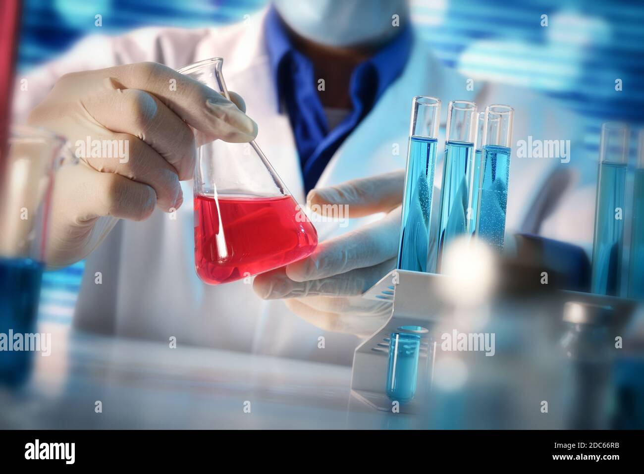 Das Detail des Wissenschaftlers, der sorgfältig bei der roten Flüssigkeit in der Flasche auf dem Labortisch manipuliert. Horizontale Zusammensetzung. Vorderansicht. Stockfoto