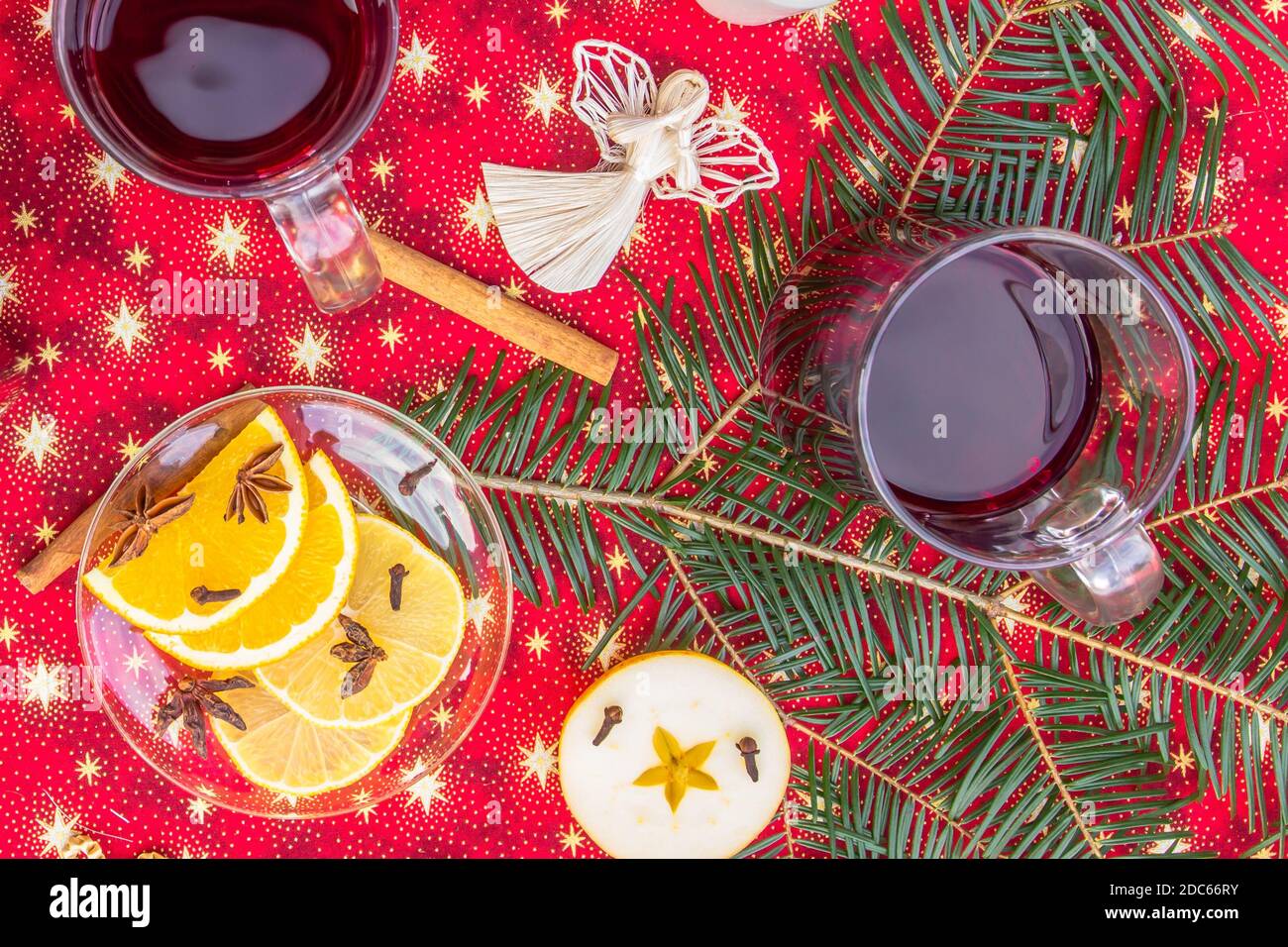 Zwei Tassen heißen Wein oder Gluhwein mit Zimt, Gewürzen und Orangenscheiben auf rotem Weihnachtshintergrund Draufsicht. Traditionelles Getränk im Winterurlaub.Glühwein wi Stockfoto