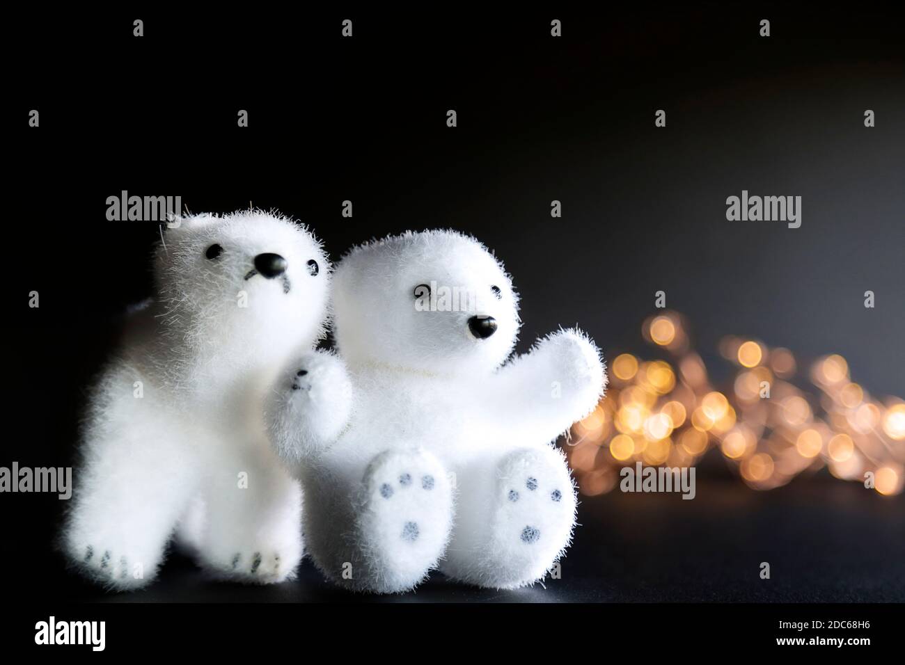 Zwei Eisbären Spielzeug und einige Lichter vor schwarzem Hintergrund Stockfoto