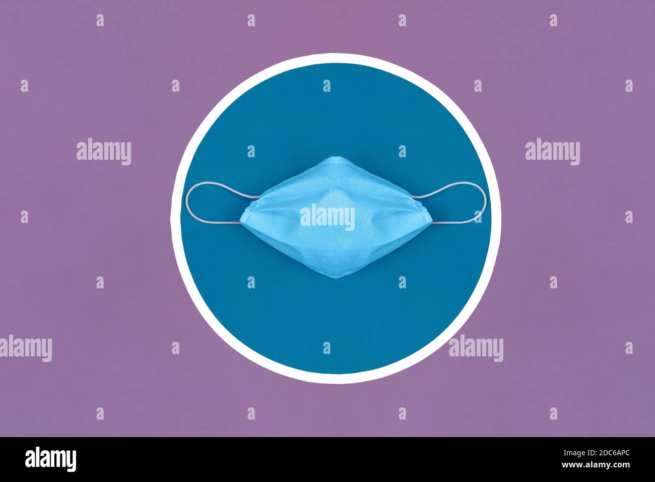 Eine isolierte medizinische schützende chirurgische Maske über einem blauen und weißen Pflichtschild auf einem violetten Stoff gemalt. Tägliche Regeln und Empfehlungen. Stockfoto