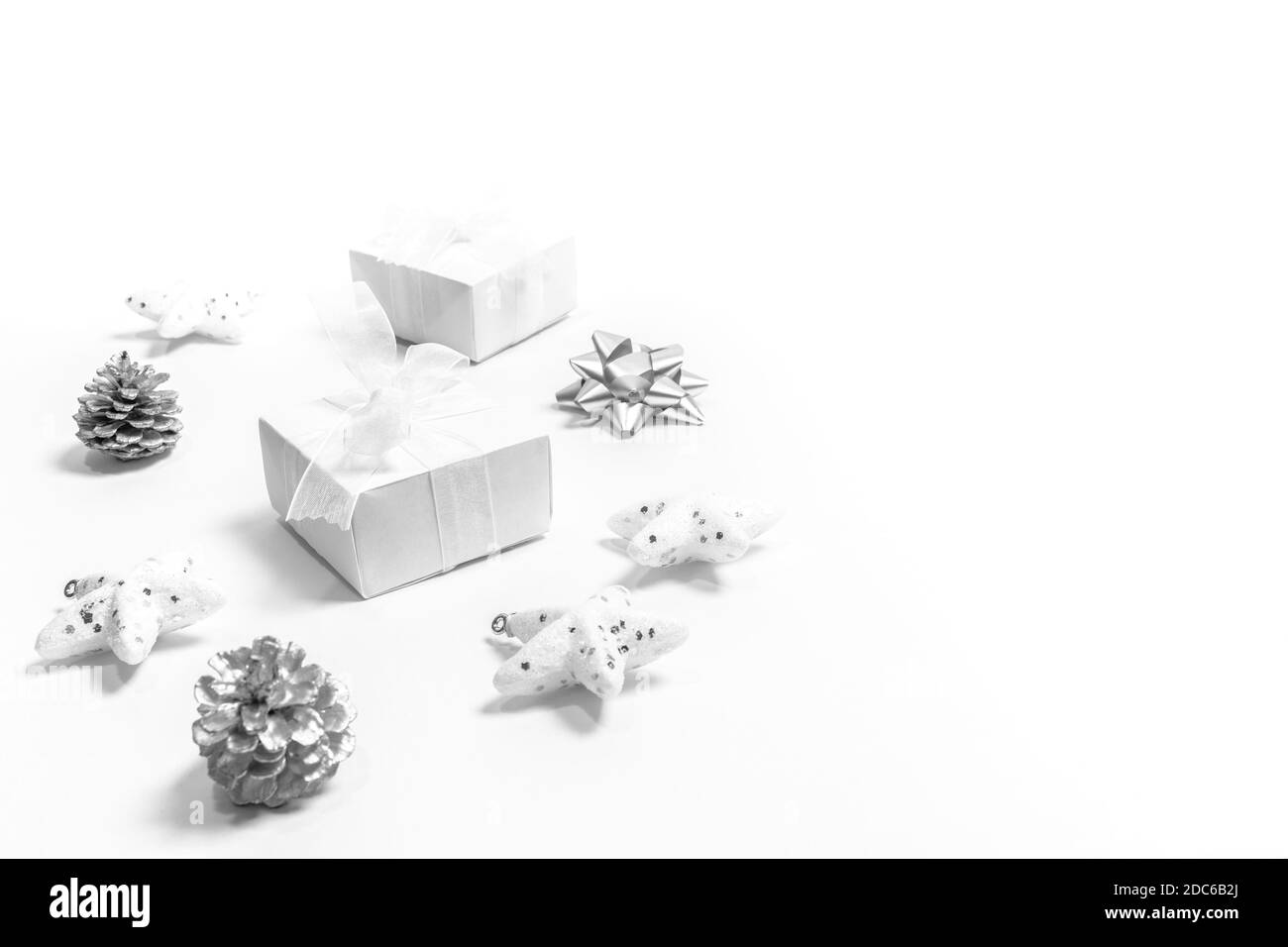 Anordnung von weißen und silbernen Weihnachtsdekorationen: Sterne, zwei DIY Geschenkboxen, Tannenzapfen als Kreis auf weiß ausgelegt. Weihnachten modern minimal nordic c Stockfoto